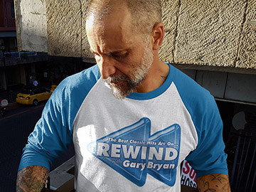 Guy wearing a White and Blue Rewind with Gary Bryan Baseball T-Shirt
