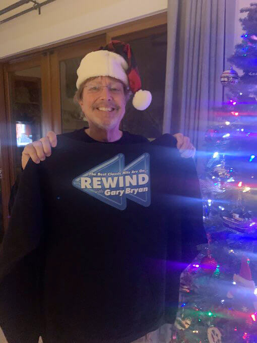 Photo of Fan Duane Fox holding a dark hoodie with the Rewind with Gary Bryan logo