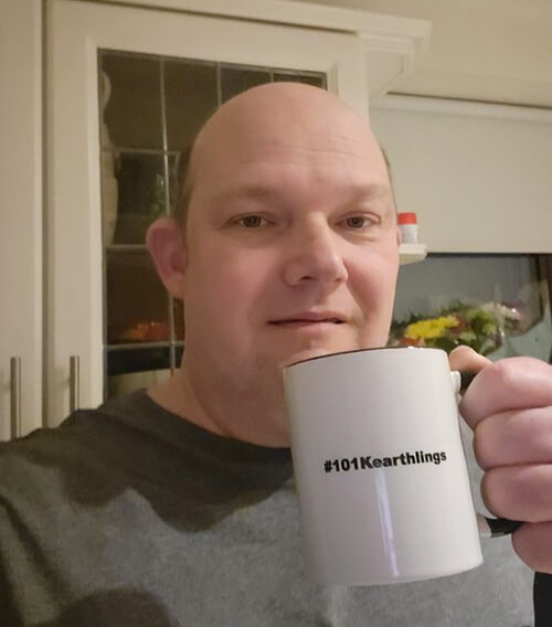 Photo of Fan of the Month Clive holding up a white coffee mug with the hashtag 101Kearthlings