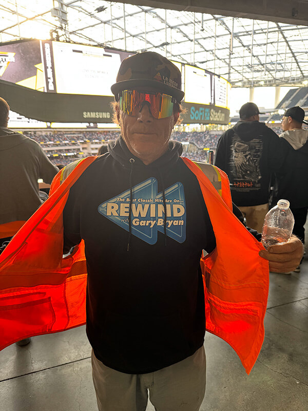 June_2025_Dave-2_600_opt A man with sunglasses and a hat wearing a black hoodie with the Rewind with Gary Bryan logo